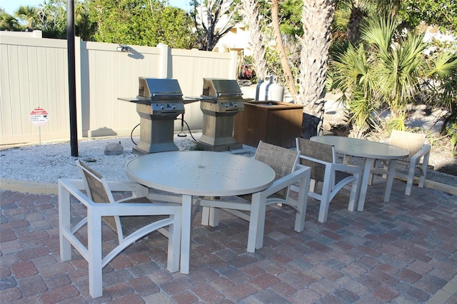 view of patio / terrace with a grill, outdoor dining space, and fence