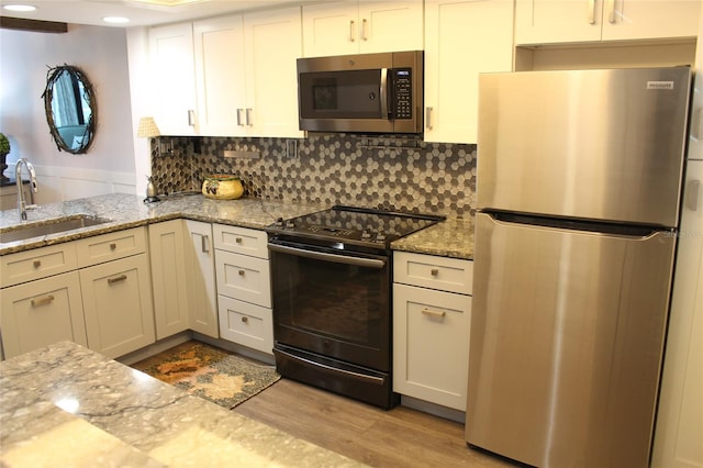 979 E Gulf Dr Unit D402, Sanibel, FL 33957 - kitchen featuring light wood finished floors, stainless steel appliances, a sink, decorative backsplash, and light stone counters