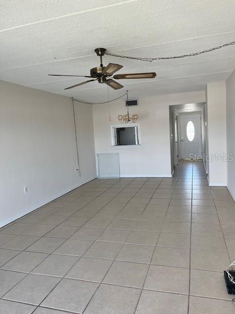 unfurnished living room with visible vents, baseboards, light tile patterned floors, a textured ceiling, and a ceiling fan