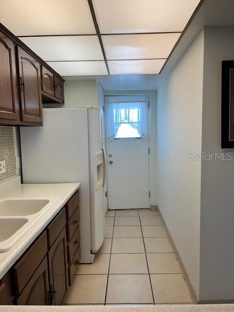 laundry room with a sink, baseboards, and light tile patterned flooring