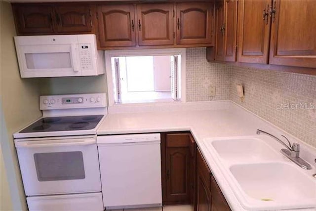 kitchen with white appliances, light countertops, brown cabinets, and a sink