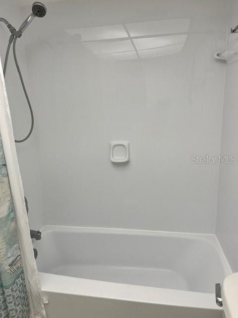 bathroom featuring toilet, shower / bath combo, and a drop ceiling