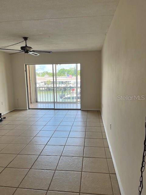 spare room featuring light tile patterned floors, ceiling fan, and baseboards