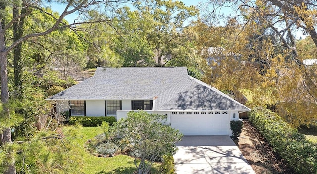 ranch-style house featuring stucco siding, driveway, an attached garage, and a shingled roof