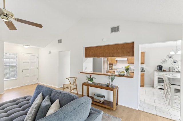 living area with visible vents, light wood-style flooring, ceiling fan with notable chandelier, and high vaulted ceiling