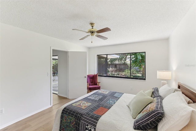 bedroom with light wood finished floors, baseboards, a textured ceiling, and ceiling fan