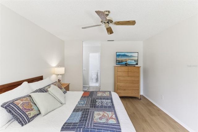 bedroom featuring wood finished floors, visible vents, baseboards, a textured ceiling, and connected bathroom