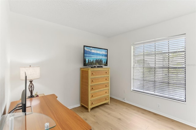 office area featuring a textured ceiling, baseboards, and light wood-style floors