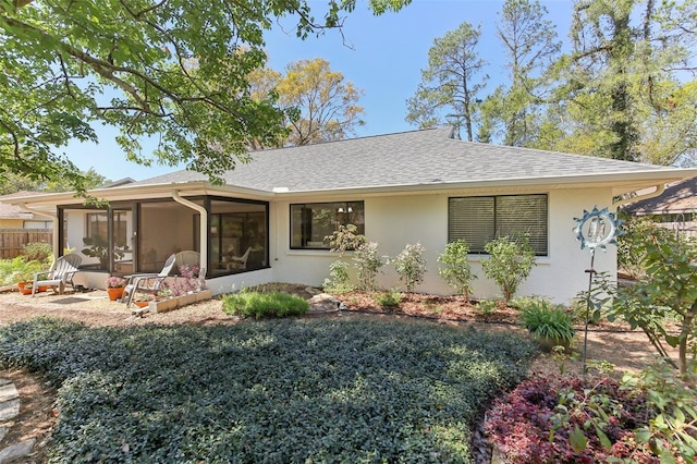 view of front of property featuring stucco siding, fence, a sunroom, and roof with shingles