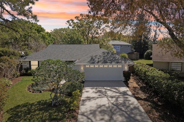 single story home featuring a front lawn, concrete driveway, a garage, and roof with shingles