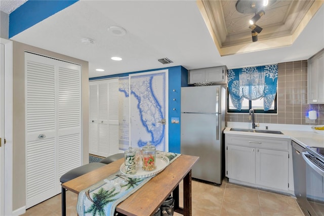 kitchen featuring visible vents, a sink, stainless steel appliances, a raised ceiling, and tasteful backsplash