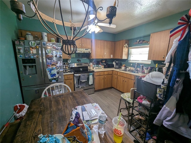 kitchen with stainless steel electric stove, extractor fan, light countertops, light wood-style floors, and refrigerator with ice dispenser