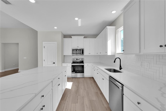 17526 SW 25th Cir, Ocala, FL 34473 - kitchen featuring appliances with stainless steel finishes, light wood-type flooring, tasteful backsplash, white cabinetry, and light stone countertops