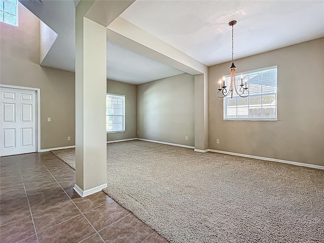 carpeted empty room with a chandelier, tile patterned floors, and baseboards