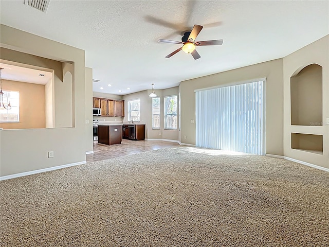 unfurnished living room featuring a textured ceiling, baseboards, visible vents, and light carpet