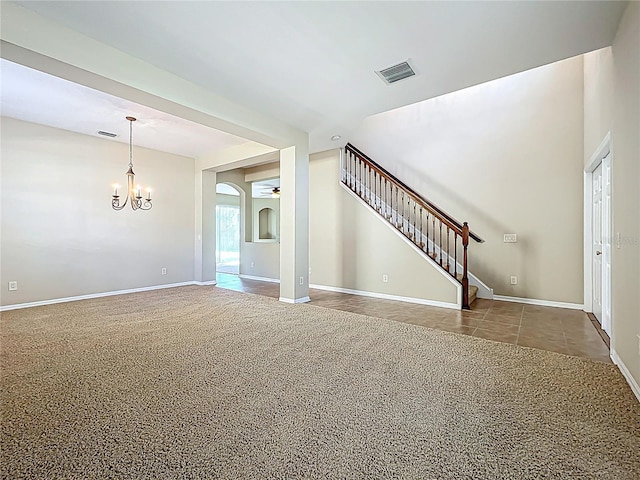 unfurnished living room featuring visible vents, stairway, an inviting chandelier, and carpet floors