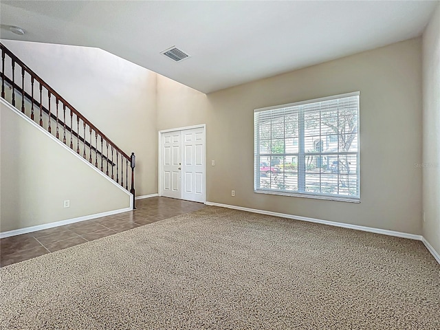 carpeted entrance foyer featuring tile patterned flooring, stairway, baseboards, and visible vents