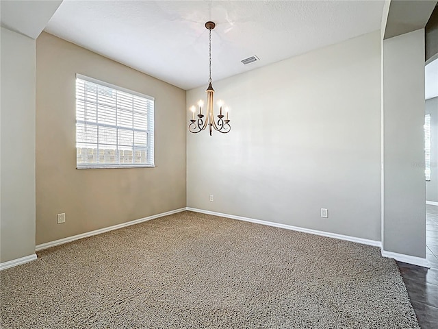 empty room with baseboards, visible vents, and a chandelier