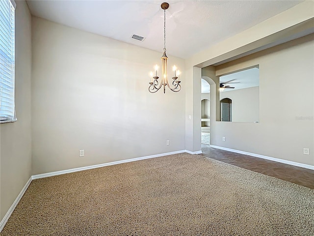 unfurnished room featuring visible vents, baseboards, dark carpet, ceiling fan with notable chandelier, and arched walkways