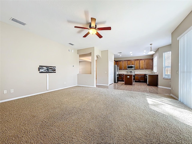 unfurnished living room with light colored carpet, baseboards, visible vents, and ceiling fan