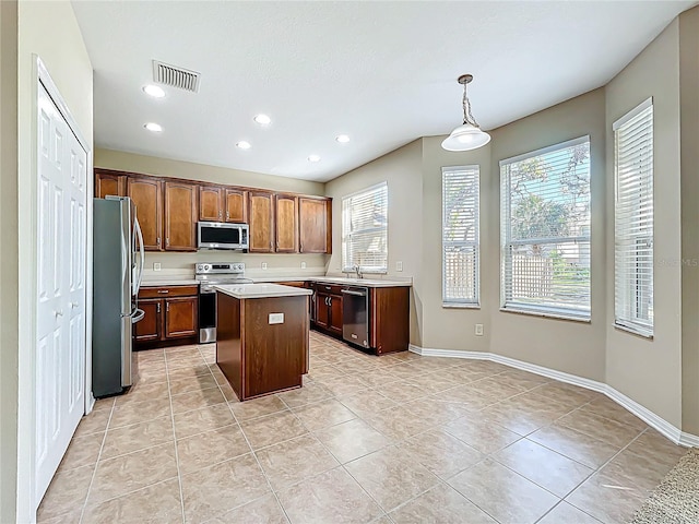 kitchen with visible vents, a kitchen island, baseboards, light countertops, and stainless steel appliances