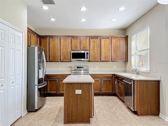 kitchen with visible vents, a sink, a kitchen island, appliances with stainless steel finishes, and light countertops