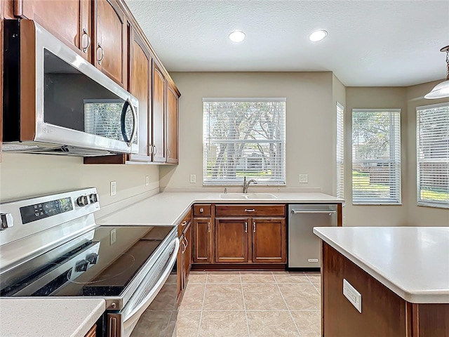 kitchen featuring light countertops, light tile patterned floors, stainless steel appliances, a textured ceiling, and a sink