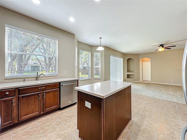 kitchen featuring a sink, arched walkways, light countertops, light colored carpet, and dishwasher