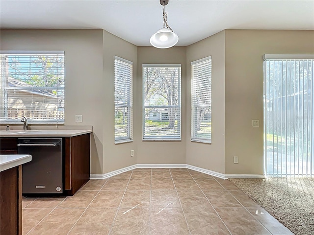 kitchen featuring decorative light fixtures, light tile patterned flooring, light countertops, baseboards, and dark brown cabinets