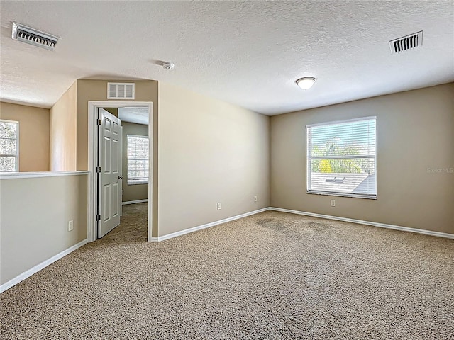 carpeted spare room featuring visible vents and plenty of natural light