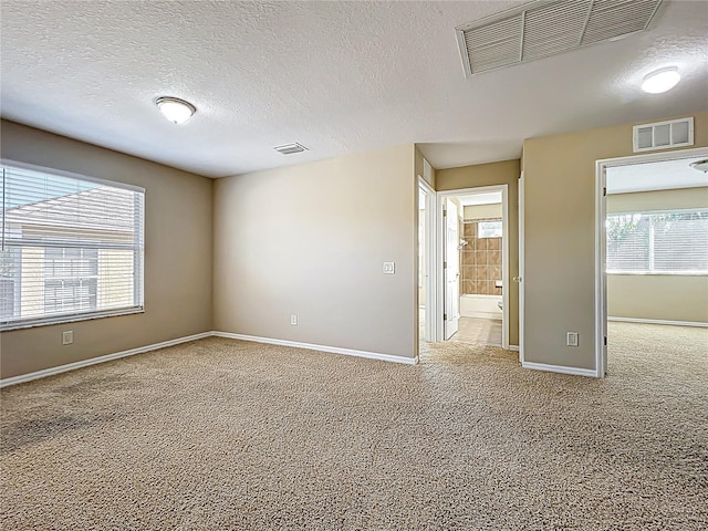 spare room with carpet, visible vents, and baseboards