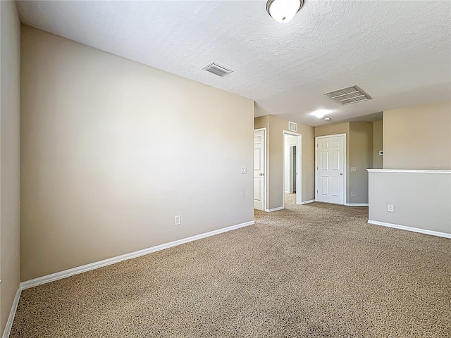 carpeted spare room with visible vents, a textured ceiling, and baseboards