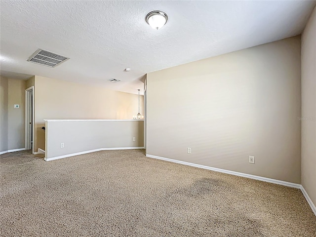 unfurnished room featuring carpet flooring, baseboards, visible vents, and a textured ceiling