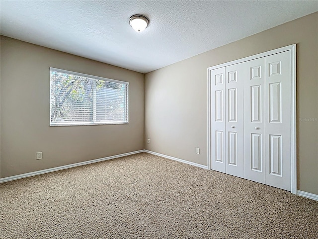 unfurnished bedroom with a closet, baseboards, carpet, and a textured ceiling