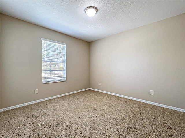 spare room featuring carpet, baseboards, and a textured ceiling