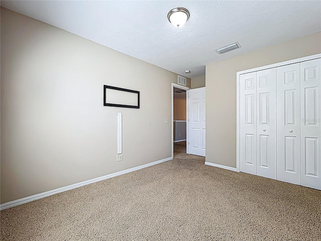 unfurnished bedroom featuring baseboards, visible vents, carpet floors, a closet, and a textured ceiling