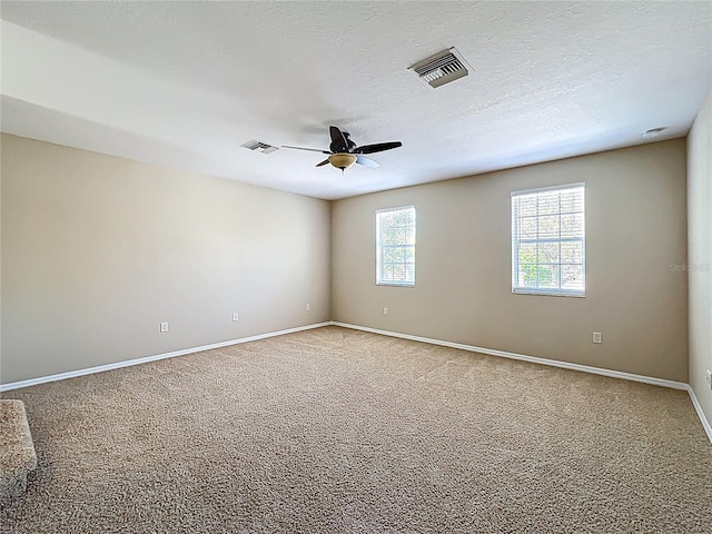 carpeted spare room featuring ceiling fan, baseboards, visible vents, and a textured ceiling