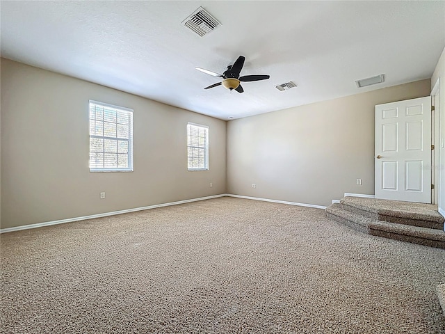 empty room featuring visible vents, a ceiling fan, and baseboards