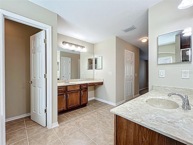 bathroom featuring tile patterned floors, visible vents, two vanities, and a sink