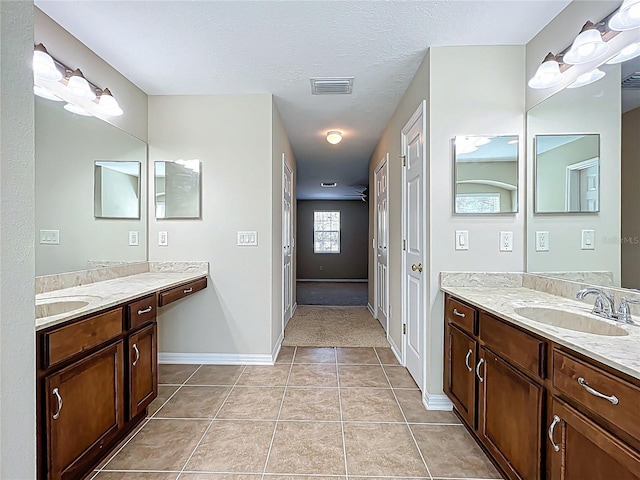 bathroom featuring tile patterned flooring, two vanities, visible vents, and a sink