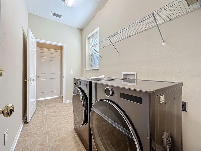 washroom with visible vents, light tile patterned floors, baseboards, laundry area, and washing machine and clothes dryer