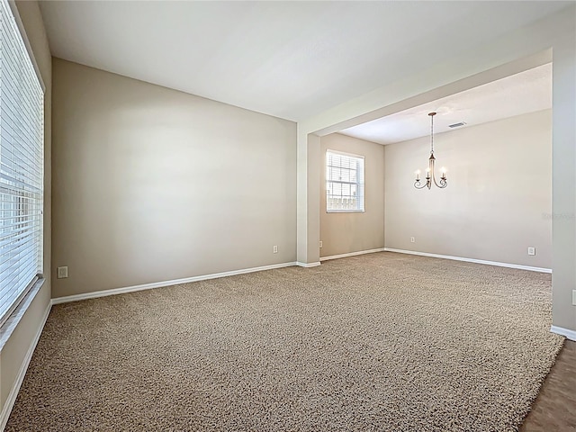 empty room featuring baseboards and a notable chandelier