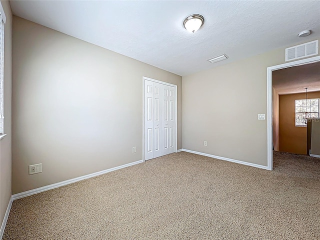 unfurnished bedroom with baseboards, visible vents, a closet, a textured ceiling, and carpet flooring