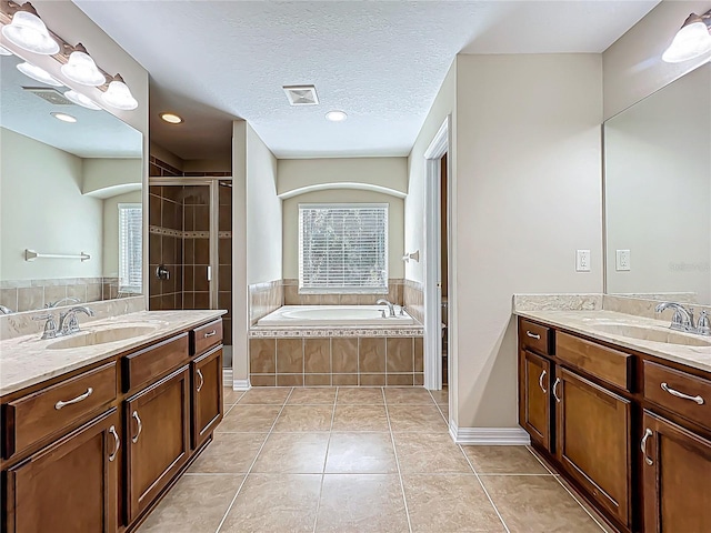 bathroom featuring a sink, a textured ceiling, a shower stall, and tile patterned floors