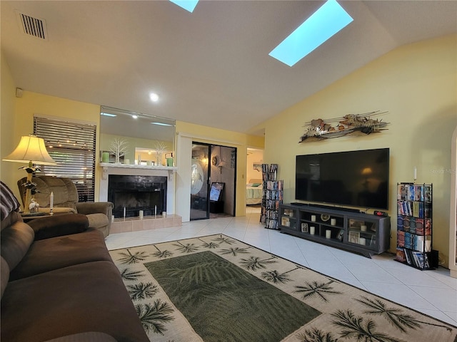 tiled living room with a tiled fireplace, lofted ceiling with skylight, and visible vents