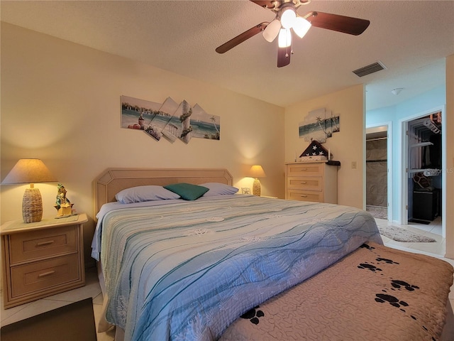 bedroom featuring light tile patterned floors, visible vents, a textured ceiling, and a ceiling fan