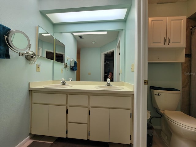 bathroom with double vanity, toilet, visible vents, and a sink