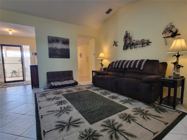 living room featuring visible vents, tile patterned flooring, and vaulted ceiling