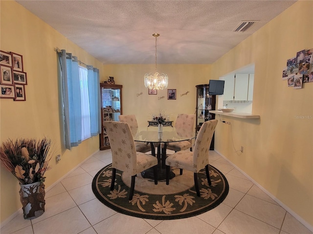 dining area featuring visible vents, a notable chandelier, light tile patterned flooring, and a textured ceiling