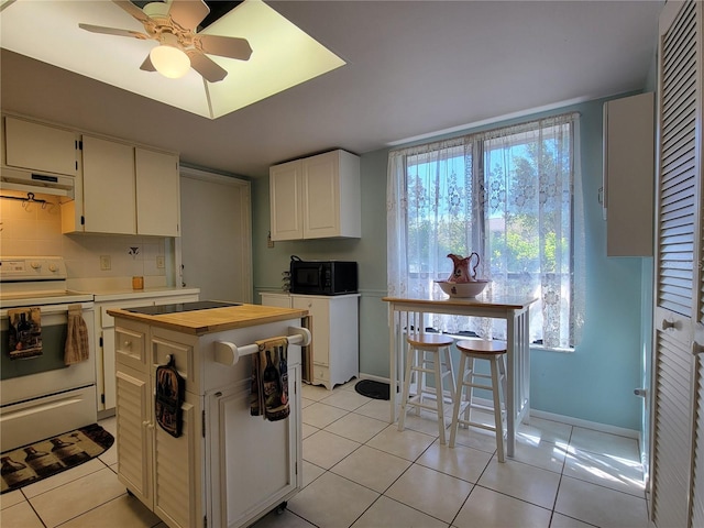 kitchen with white electric range, wood counters, under cabinet range hood, light tile patterned flooring, and black microwave